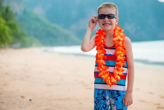 Boy in flower lei and sunglasses on the beach