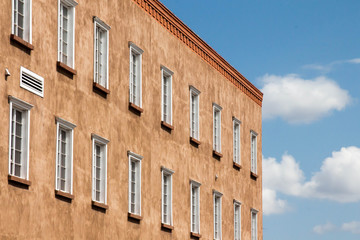 Two rows of white windows in an adobe building