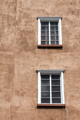 Fototapeta na wymiar Two white windows in brown adobe wall