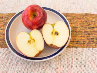 Red and fresh apple cut into a white bowl on a cotton towel for delicious, tasty and healthy food.