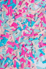 vertical background of the small cut pieces of colored paper pink and blue closeup. the concept of the party