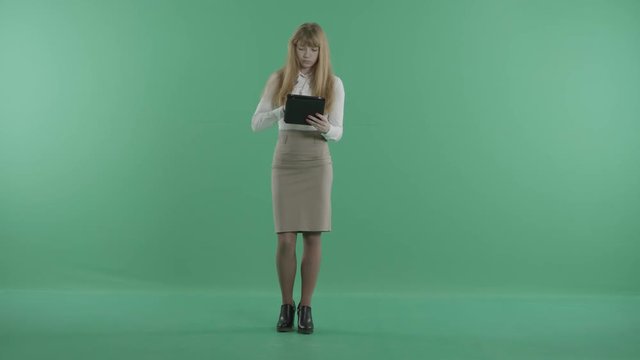 a redhead woman stands with a tablet in hands