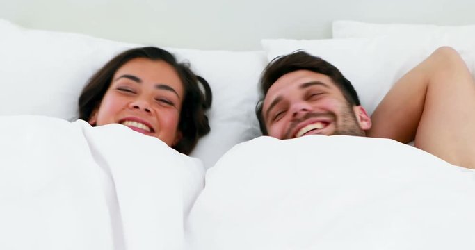 Portrait of couple sleeping under white blanket on bed