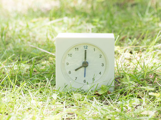 White simple clock on lawn yard, 8:00 eight o'clock