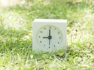 White simple clock on lawn yard, 9:00 nine o'clock