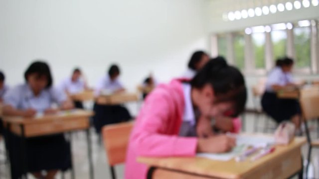 Blurred of Asian Students groups doing multiple-choice quizzes or testing exams answer sheets exercises on old wood table In secondary school, college university classroom in education concept