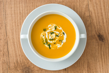 Pumpkin soup in white bowl on wooden table
