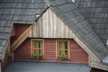 A small window with red geranium flowers/