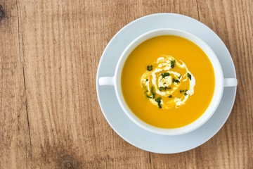 Pumpkin soup in white bowl on wooden table
