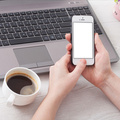 A woman holds smartphone white phone in the workplace in the room. Woman using a mobile phone for work.