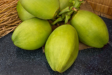 Fresh green coconuts branch on black granite. Ripe coconuts on the farm. Vegetarian, vegan food. For gourmet. Raw diet. Fruit with from tropical zone. Selective focus.