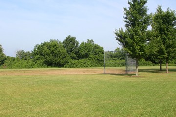 The small ball field in the park on a sunny day.