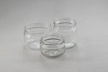 Small glass jars with carvings on a gray background, without covers.
