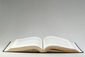 Disclosed book above on a gray background. Reading. Background for postcard, cover, textspace.