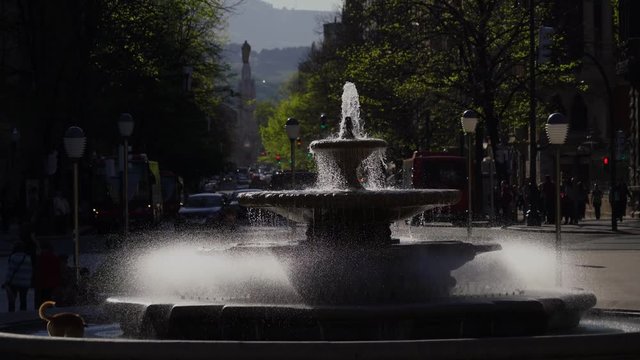 Brunnen am Plaza Moyua im Zentrum der Kulturhauptstadt Spaniens, Bilbao an einem heißen Sommertag mit Jesus-Statue im Hintergrund