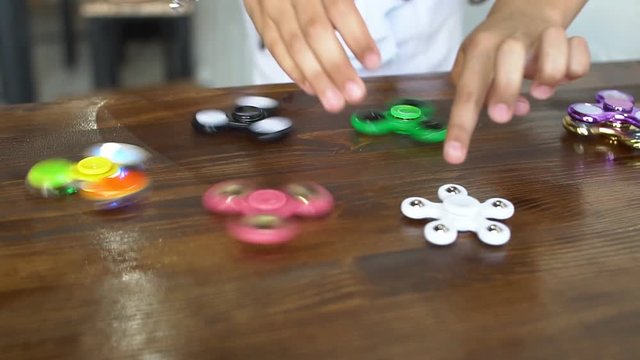 Hand spinner rotating on child's hand, slow motion.
