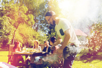 man cooking meat on barbecue grill at summer party