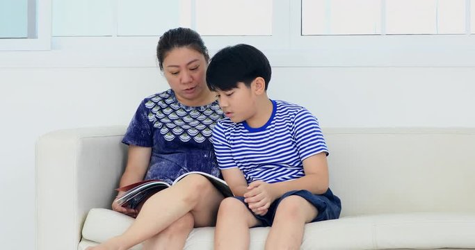 Happy young mother with her son reading in home together