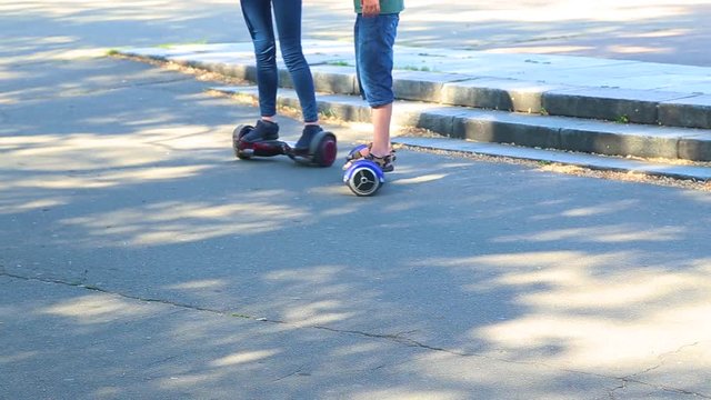 Young boy learns to ride electrical scooter outdoors in city park on sunny summer day. Real time full hd video footage.