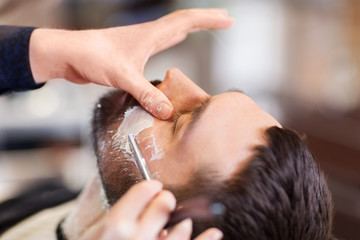 man and barber with straight razor shaving beard