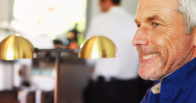 Smiling mature man drinking beer at counter