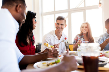 Obraz na płótnie Canvas happy friends eating and talking at restaurant