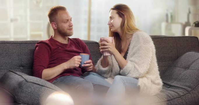 Sweet young couple drinking tea on couch