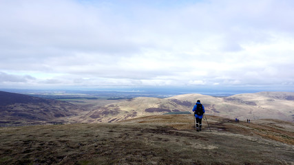 Hill walker on a country path looking down towards a lake in a country landscape. 