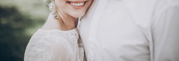 stylish wedding bride smiling. modern bride hugging groom, lips and earrings close up. fine art...