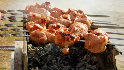 Barbeque skewers with meat rotating and cooking on the grill outdoors with smoke