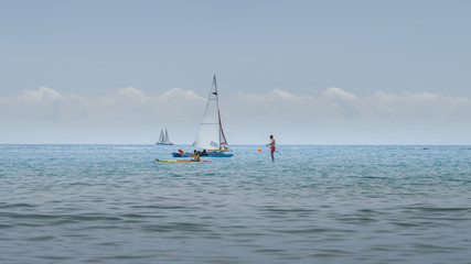 Naklejka premium Rest on sea. Sea kayak, boats with sail, stand up paddler. Outdoor sea sporting activity