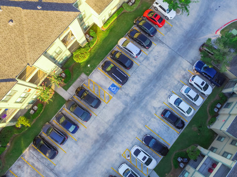 Aerial view of apartment garage with covered parking lots, cars and green trees at multi-floor buildings complex in Humble, Texas, US early morning. Urban infrastructure and transportation concept.