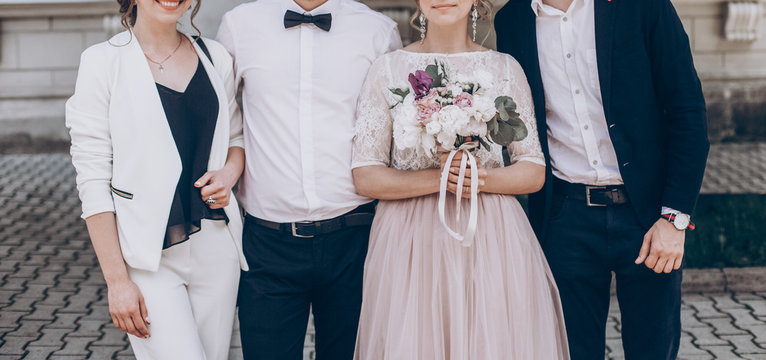 stylish wedding bride with bouquet and groom taking photo with family with bridesmaid and groomsmen after official wedding ceremony