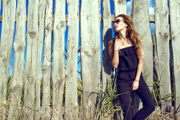 Young beautiful model with long chestnut hair wearing black strapless jumpsuit and trendy...