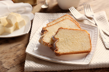 Plate with delicious sliced butter cake on wooden table
