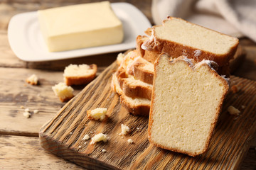 Wooden board with delicious sliced butter cake on table