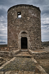 The ruined stone shrine of a traditional Greek windmill.