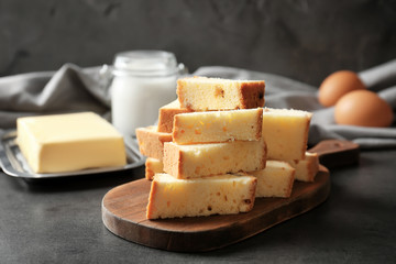 Wooden board with delicious sliced butter cake on table