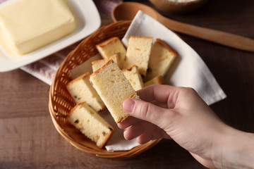 Closeup view of woman holding butter cake piece over table