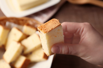 Closeup view of woman holding butter cake piece over table