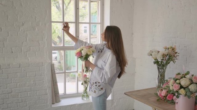 beautiful young florist girl taking selfie with bouquet at her flower studio