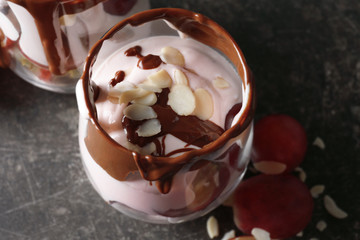 Delicious yogurt parfait with chocolate sauce and almond petals in glass on table