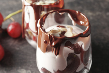 Delicious yogurt parfait with chocolate sauce in glass on table