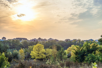 Autumn sunset over the roofs of suburban houses. Evening landscape in backlight sunlight. Belgorod Region, Russia.