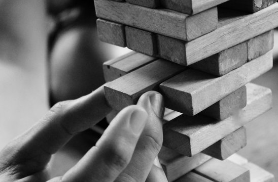 hand playing jenga with wood blocks, puzzle 