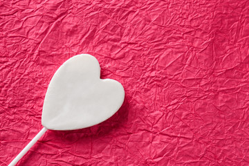 Fototapeta premium Tasty candy in shape of heart on color crumpled paper