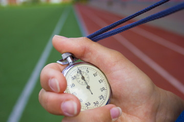 Close up of coach is holding a stopwatch against race track
