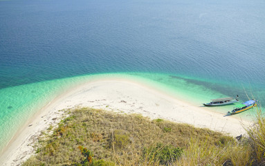 Top view of two boats at the coast of a white sand beach surrounded by  blue turquoise colored...