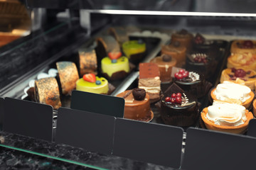 Fridge with cakes in shop, closeup