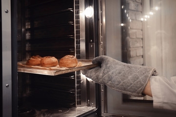 Woman holding tray with buns in bakery